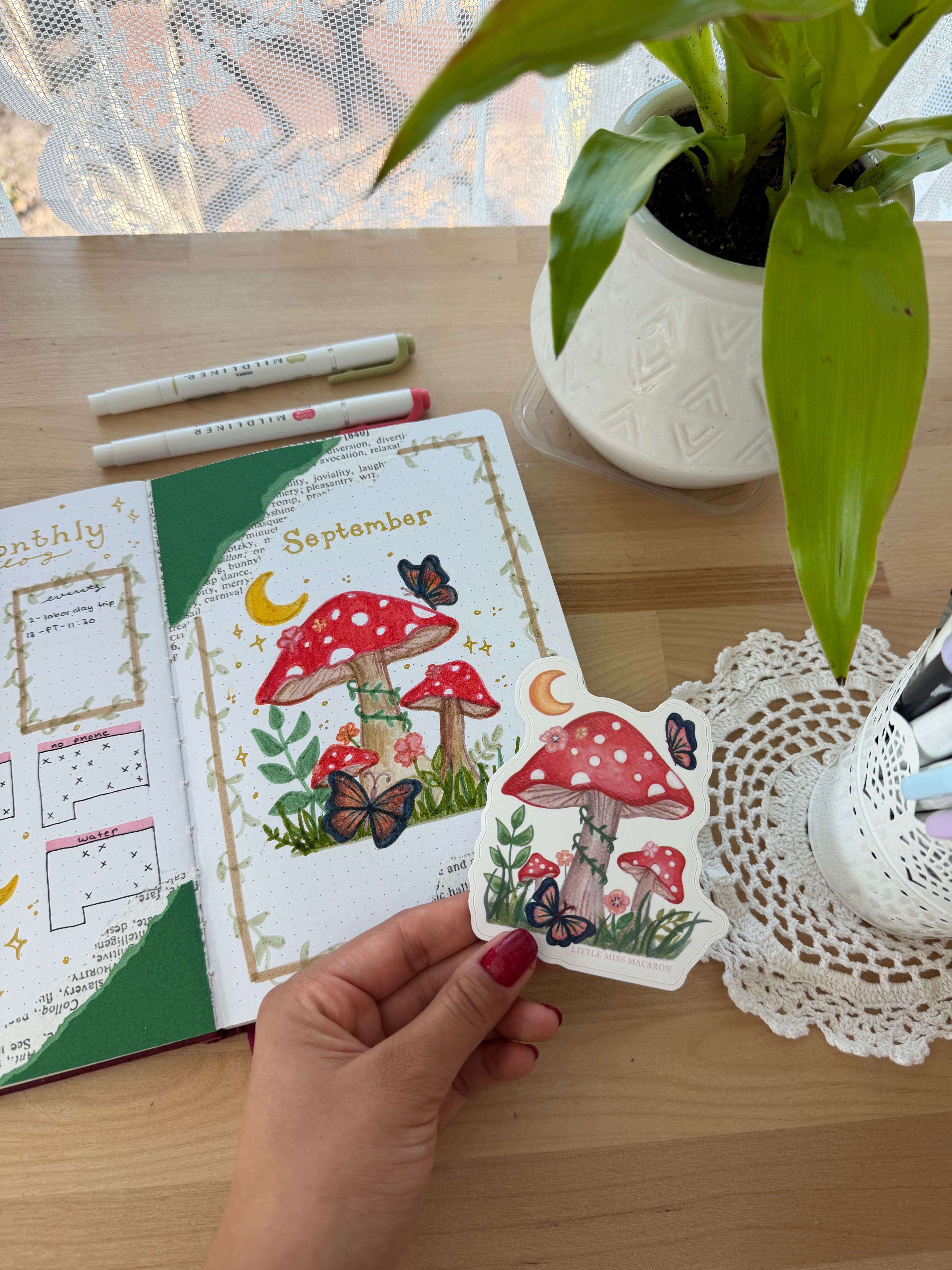 Hand holding a colorful card with nature-themed illustrations on a wooden table.
