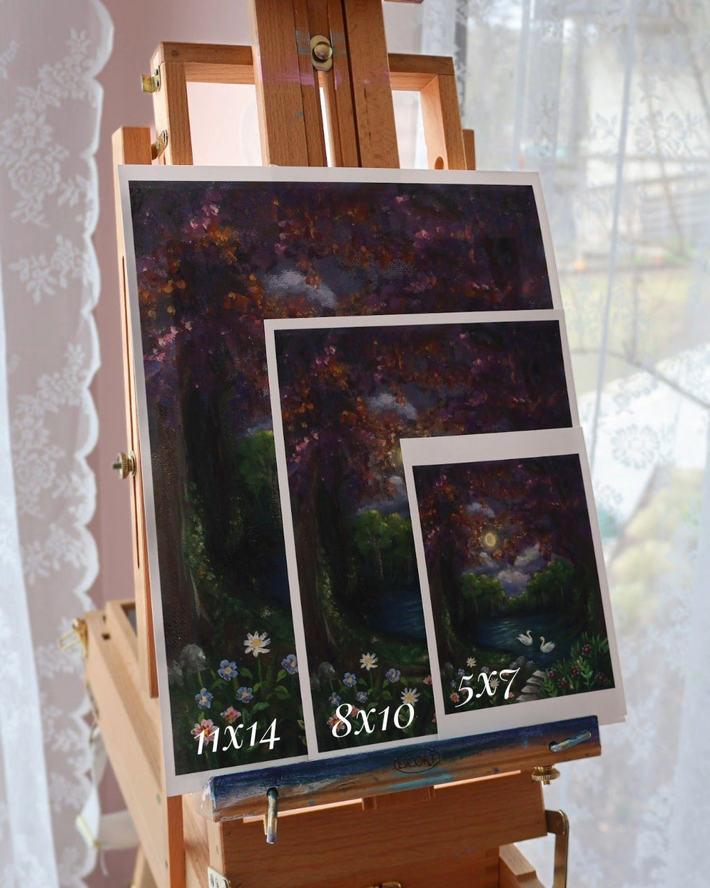 Easel with framed artworks on a white lace curtain background